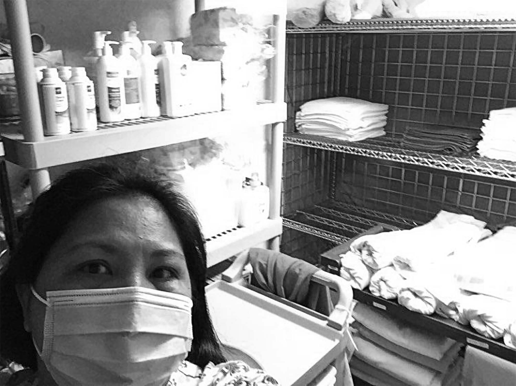 Woman in a supply closet staring at the camera wearing a mask